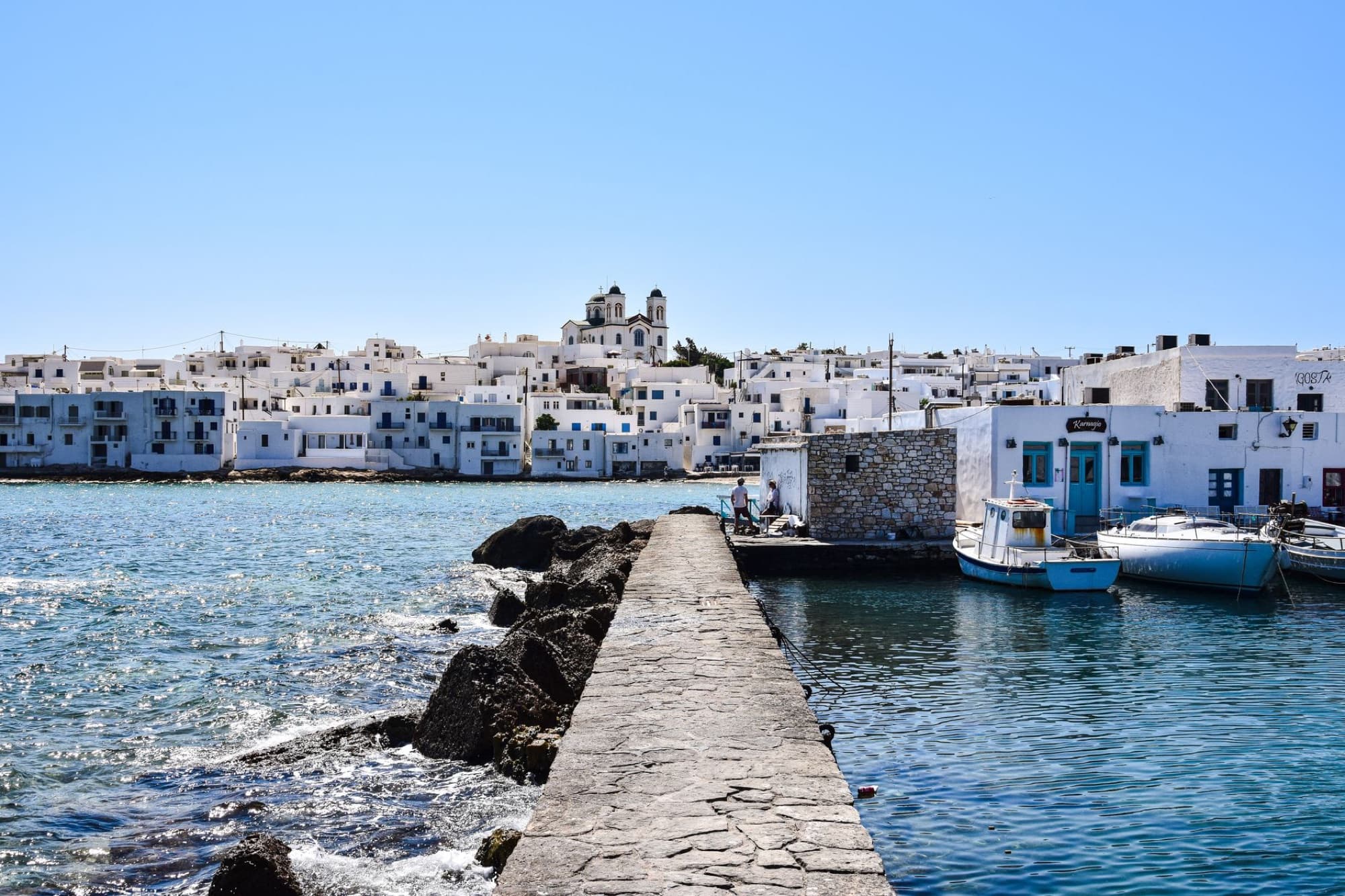 Charming white-washed buildings and boats along Paros Island's scenic waterfront pier.