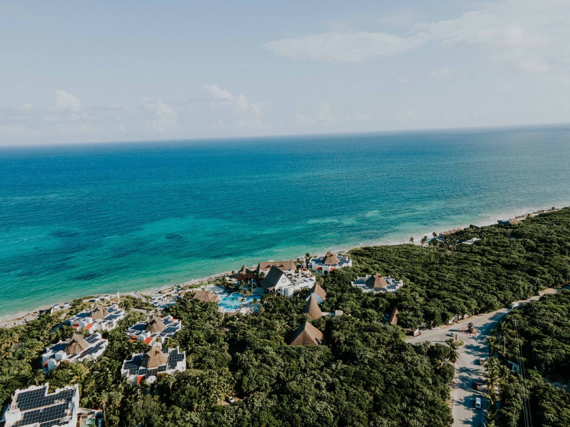 Stunning aerial view of a luxury beachfront resort surrounded by lush greenery in Tulum, Mexico.