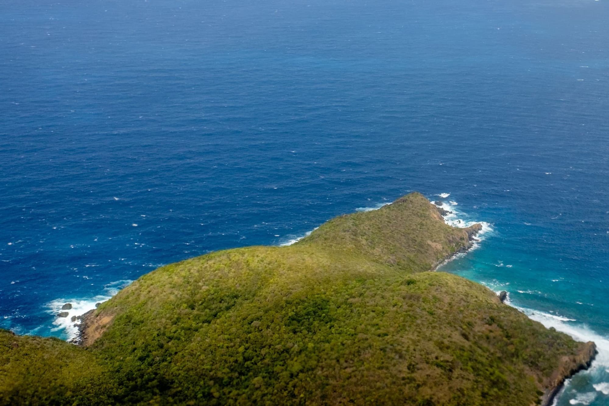 Stunning aerial shot capturing a remote island's green landscape meeting the vast blue ocean.