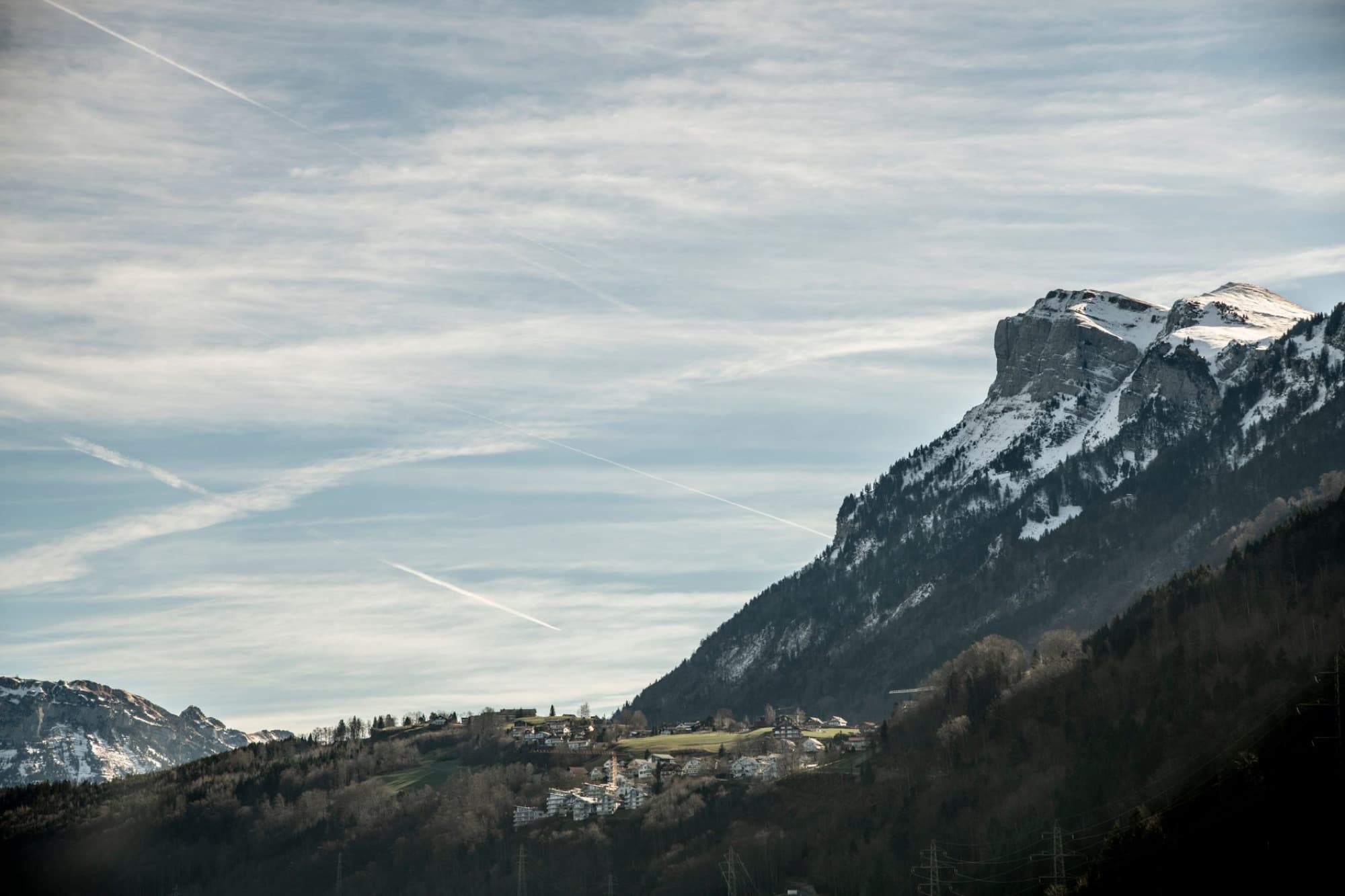 Scenic aerial view of the Swiss Alps with snow-capped mountains and quaint village.