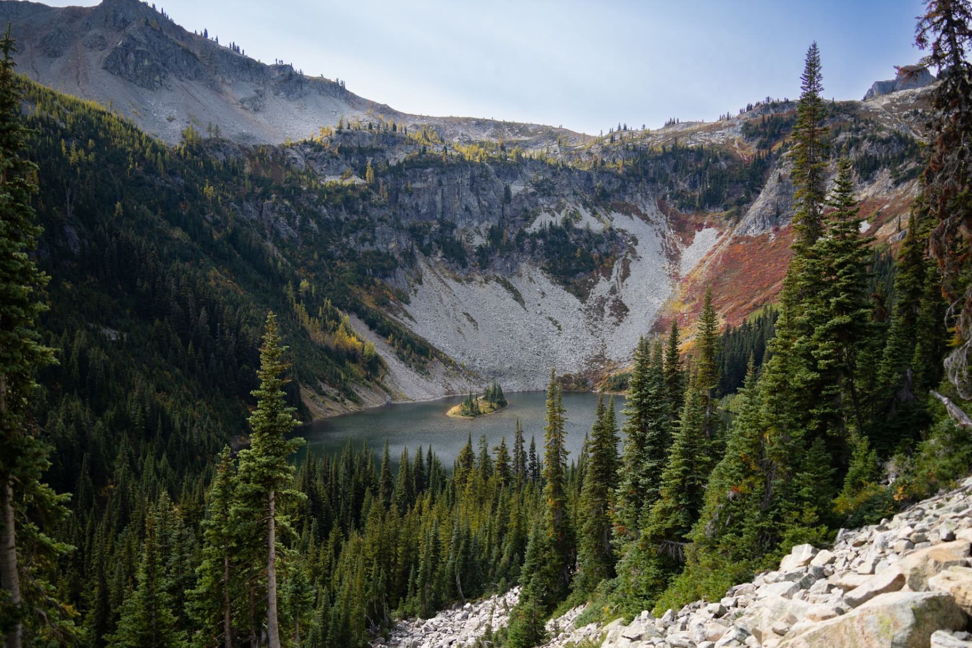 Larch Lake surrounded by autumn trees in the mountainous Washington State wilderness.